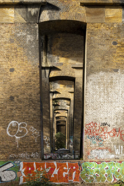 Underneath of a brick bridge with graffiti