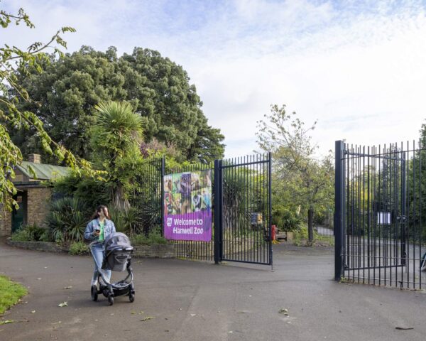 A lady pushing a pram in front of a zoo